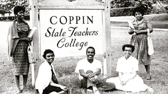 在一张黑白照片中，5名学生围绕着科平州立师范学院的标志摆姿势。