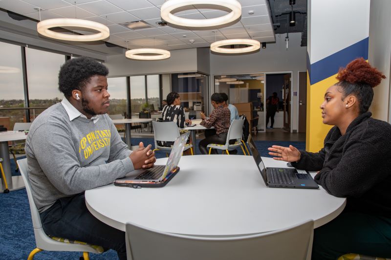 两个学生谈论坐在一张桌子在鹰成就中心