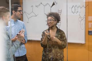 三个大学生在实验室做化学作业。一个是用记号笔在透明的玻璃板上写字。