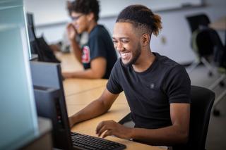 一个微笑的男学生在电脑上打字