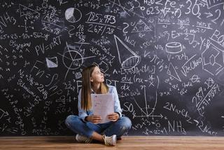 一个女学生坐在大黑板前做数学题。